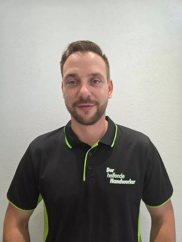 Portraitfoto von Nico Berger, Inhaber von Der helfende Handwerker, im schwarzen Firmen-Poloshirt mit neongrünem Detail